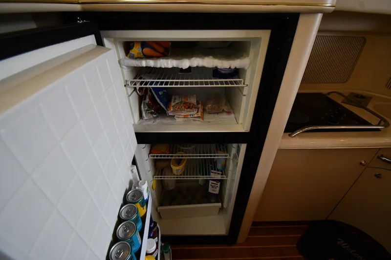 Slide: The Image of Refrigerator interior on 1998 Sea Ray 400 Sedan Bridge yacht, stocked with food and drinks. - 49