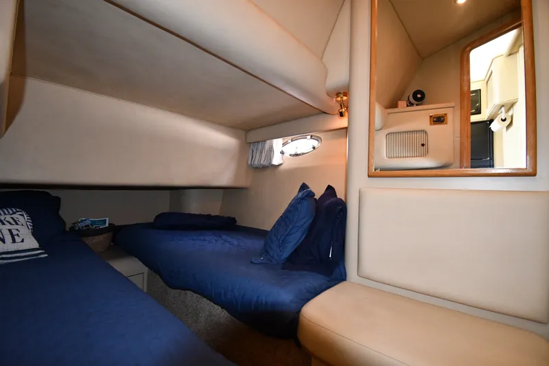 Slide: The Image of 1998 Sea Ray 400 Sedan Bridge cabin with twin beds, blue bedding, and a mirror. - 37