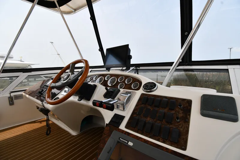 Slide: The Image of 1998 Sea Ray 400 Sedan Bridge helm with wooden steering wheel and control panel. - 19