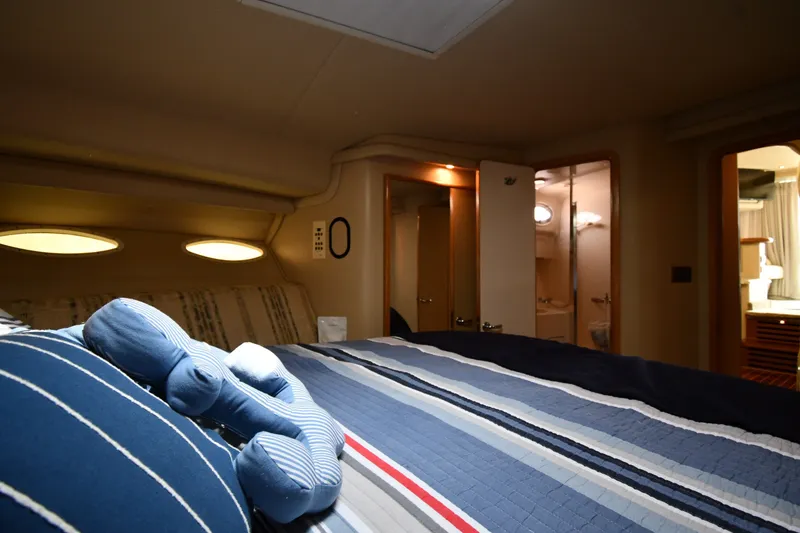Slide: The Image of Interior cabin of 1998 Sea Ray 400 Sedan Bridge with striped bedding and soft lighting. - 33
