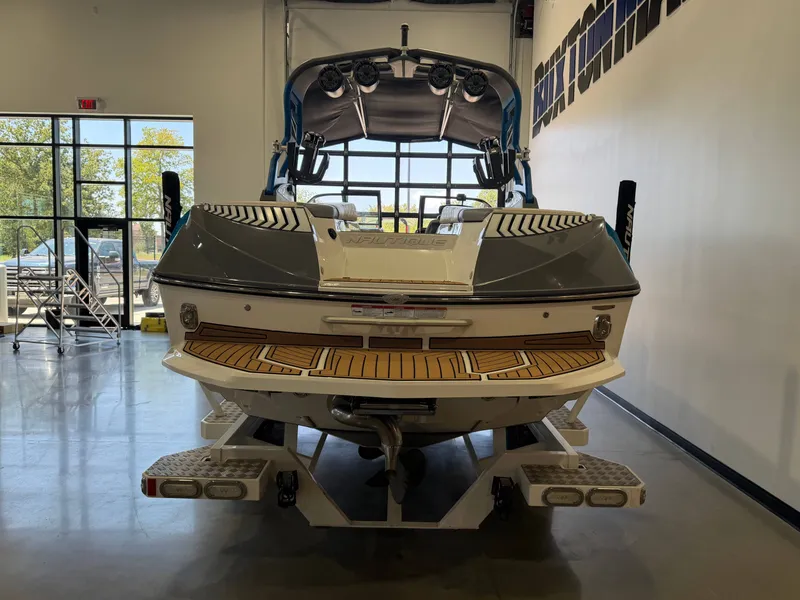 Slide: The Image of A 2019 Nautique Super Air Nautique G25 in a showroom. The boat features a modern design with a blue canopy and multiple speakers. - 3