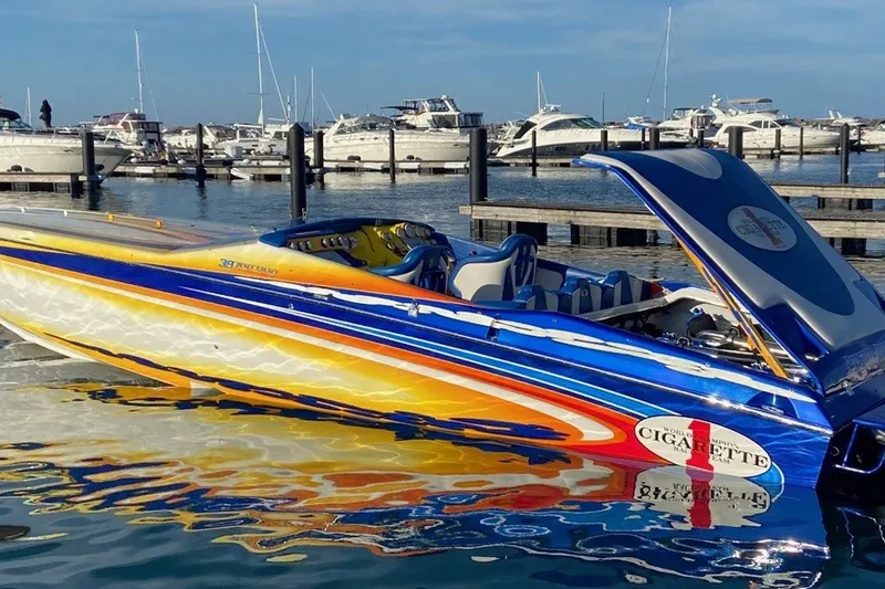 The Image of 2005 Cigarette 39' Top Gun Unlimited speedboat with vibrant colors docked at marina. - 9