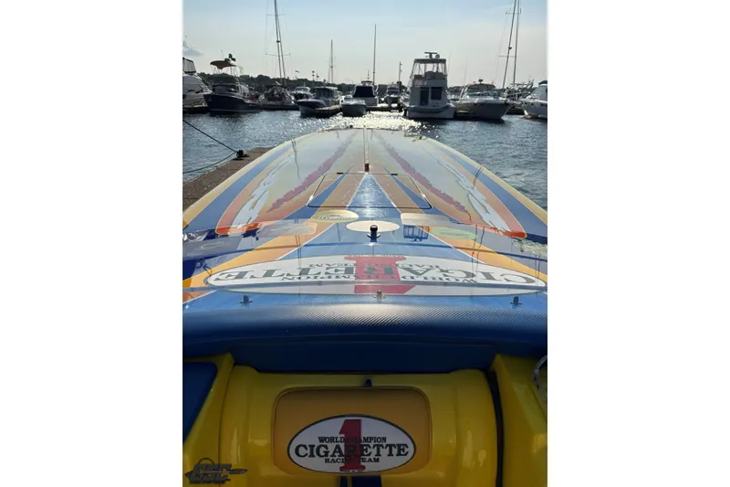 Slide: The Image of 2005 Cigarette 39' Top Gun Unlimited boat docked at marina, vibrant design, sunny day. - 18