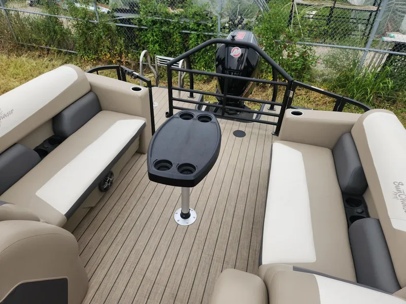 Slide: The Image of The image shows the deck of a SunChaser Eclipse 8523 LR DH pontoon boat with beige seating and a table. - 9