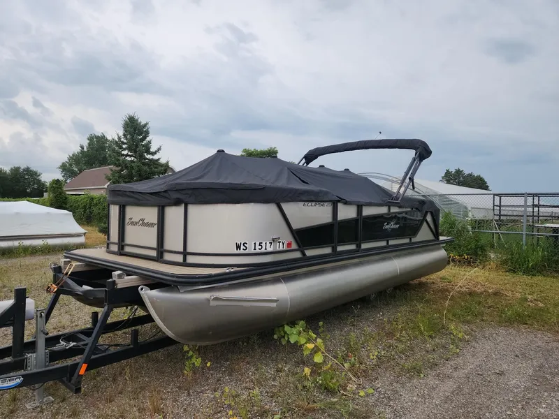 The Image of A 2023 SunChaser Eclipse 8523 LR DH pontoon boat on a trailer, featuring a black cover. - 1