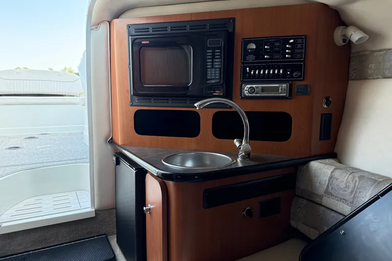 Slide: The Image of 2005 Crownline 275 CCR boat interior with kitchenette, microwave, sink, and control panel. - 16