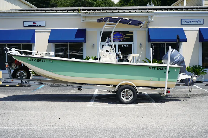 The Image of 2015 Key West 197 Skiff boat on trailer, parked outside dealership. - 1