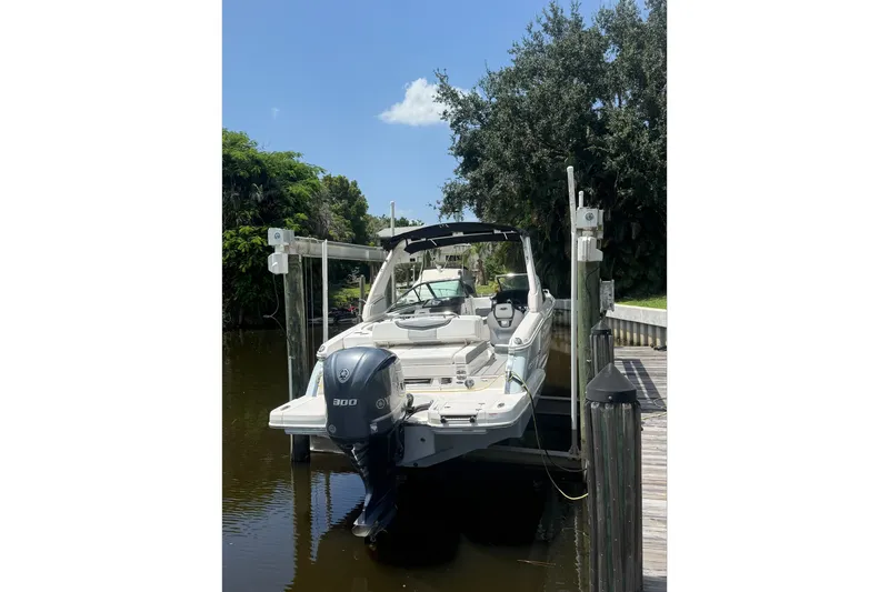 Slide: The Image of 2020 Chaparral 257 SSX boat docked on a sunny day, surrounded by lush greenery. - 5