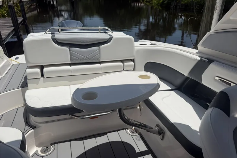 Slide: The Image of 2020 Chaparral 257 SSX boat interior with seating and table, docked by water. - 22