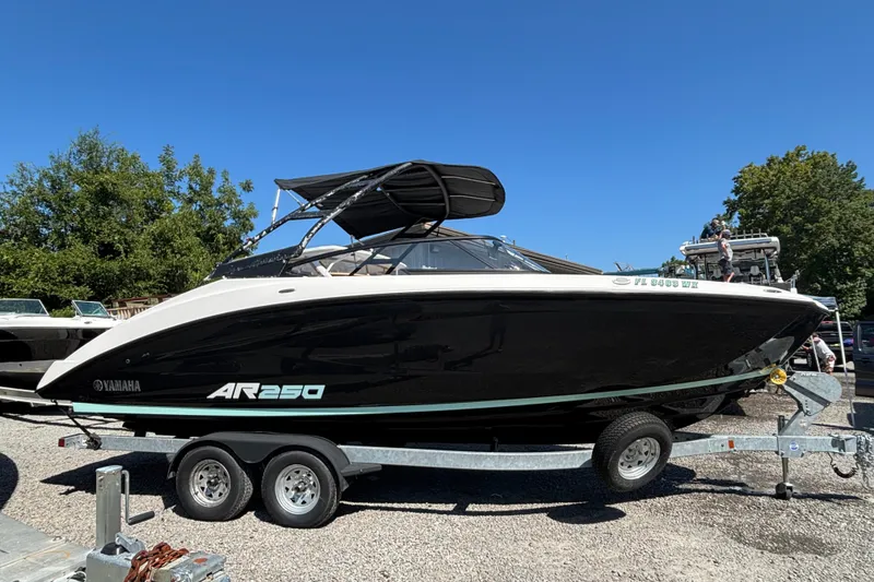 Slide: The Image of 2023 Yamaha AR250 boat on trailer, parked outdoors under clear blue sky. - 2