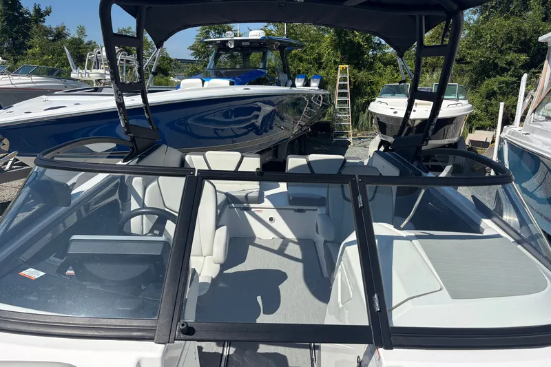 Slide: The Image of 2023 Yamaha Boats AR250, sleek design, spacious interior, docked among other boats. - 13