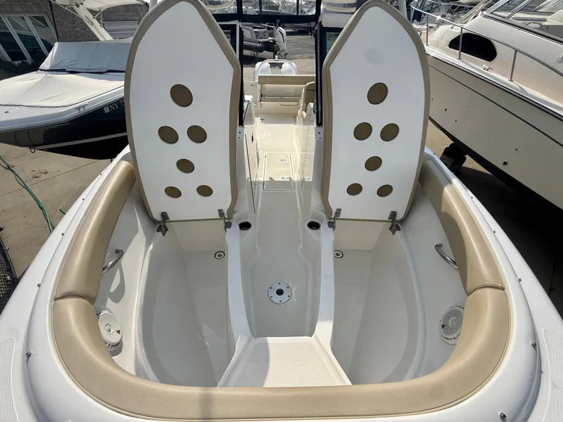 Slide: The Image of The image shows the cockpit of a 2019 Pursuit DC 265 Dual Console boat with open storage compartments. - 24