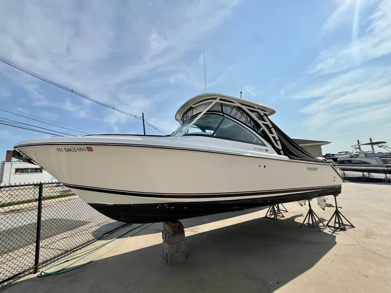 The Image of A 2019 Pursuit DC 265 Dual Console boat is on a stand in a yard. - 0