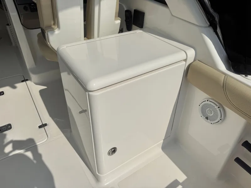 Slide: The Image of A white storage compartment on a boat with a speaker and beige seating in the background. - 12