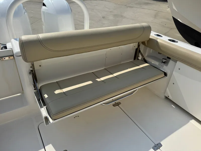 Slide: The Image of The 2019 Pursuit DC 265 Dual Console features a beige fold-down bench seat in the aft area. - 6