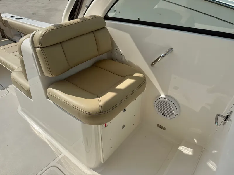 Slide: The Image of The image shows the seating area of a 2019 Pursuit DC 265 Dual Console boat with beige upholstery. - 15