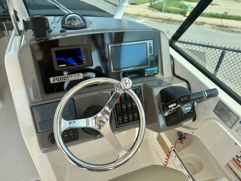 Slide: The Image of The image shows the helm of a 2019 Pursuit DC 265 Dual Console boat with modern instruments. - 20
