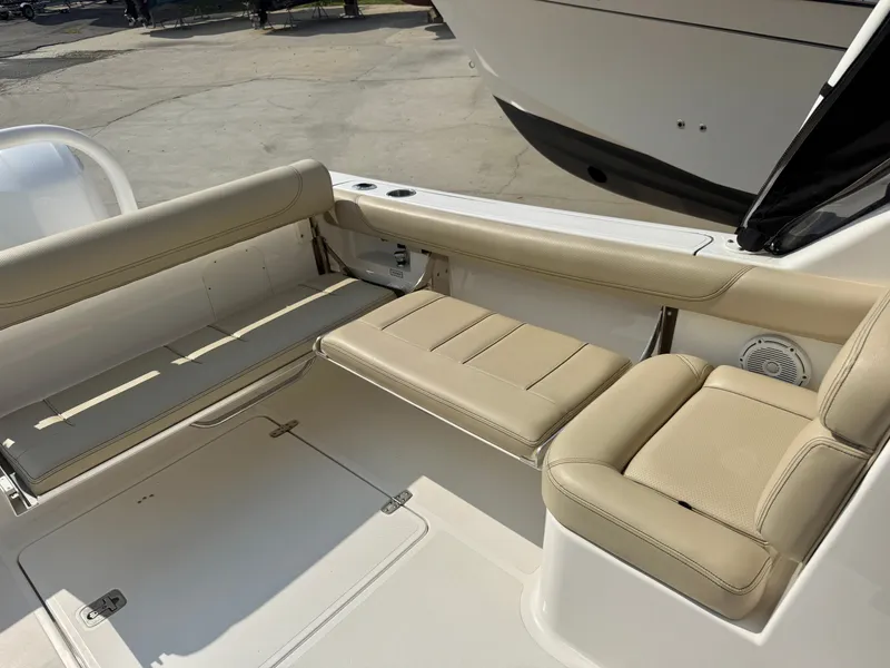 Slide: The Image of The image shows the seating area of a 2019 Pursuit DC 265 Dual Console boat with beige upholstery. - 9