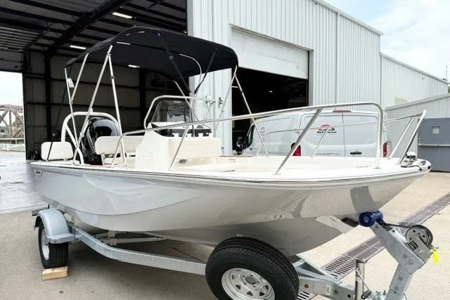 Slide: The Image of 2027 Boston Whaler 170 Montauk boat on trailer, parked outside a warehouse. - 1