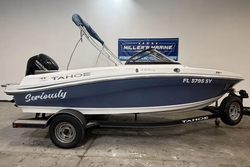 The Image of 2021 Tahoe 450 TS boat on trailer in showroom, blue and white design. - 0
