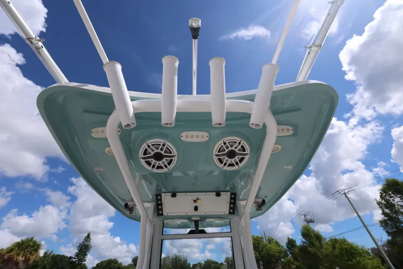 Slide: The Image of 2021 Tidewater 256 CC Adventure boat, featuring rod holders and speakers under a clear blue sky. - 18