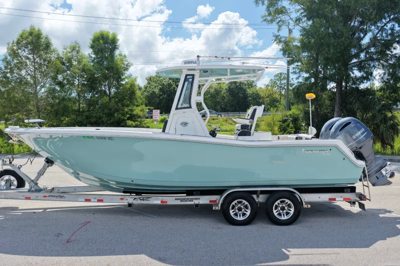 The Image of 2021 Tidewater 256 CC Adventure boat on trailer, parked outdoors under a sunny sky. - 0