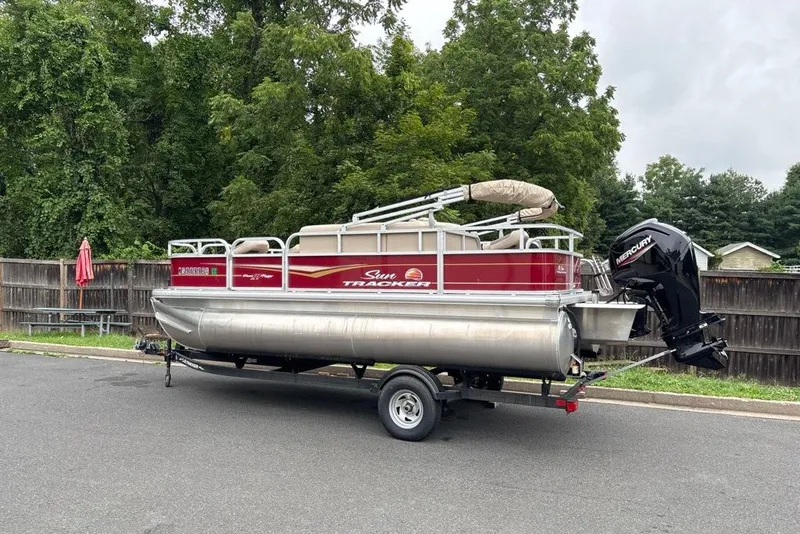 Slide: The Image of 2024 Sun Tracker Bass Buggy 18 DLX pontoon boat on trailer, parked outdoors. - 34
