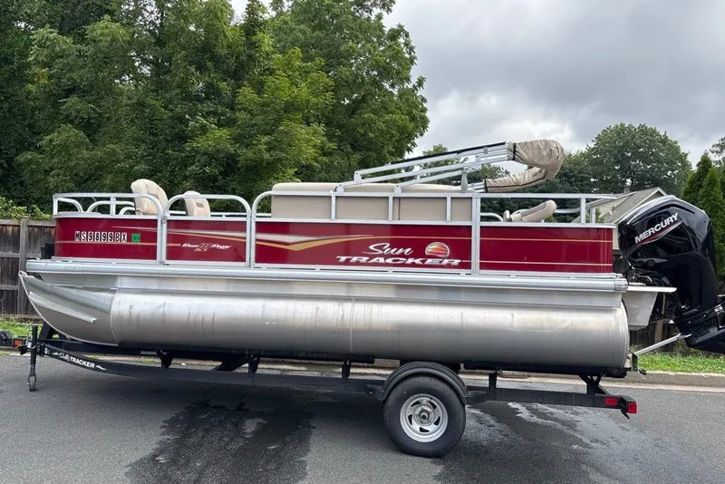 The Image of 2024 Sun Tracker Bass Buggy 18 DLX pontoon boat on trailer, parked outdoors. - 0