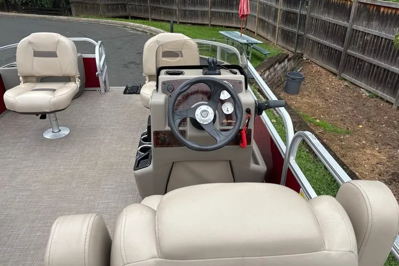 Slide: The Image of 2024 Sun Tracker Bass Buggy 18 DLX pontoon boat interior with beige seating and steering console. - 30