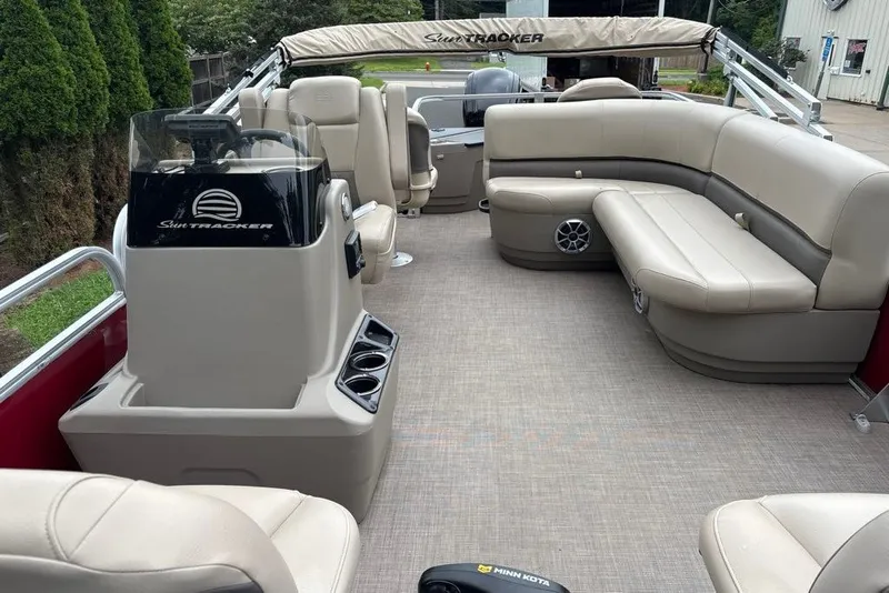 Slide: The Image of 2024 Sun Tracker Bass Buggy 18 DLX pontoon boat interior with beige seating and helm. - 17