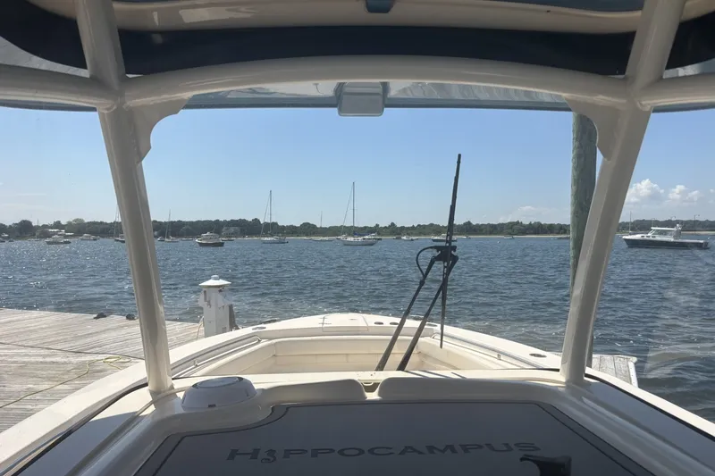 Slide: The Image of 2021 Grady-White Canyon 306 boat docked, overlooking a serene marina with sailboats. - 8