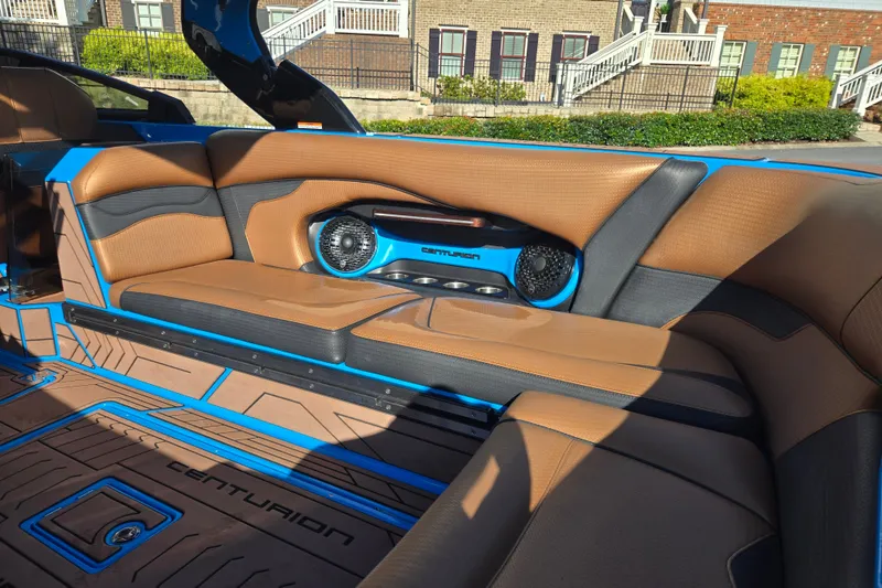 Slide: The Image of 2021 Centurion Ri257 boat interior with tan and blue seating, featuring built-in speakers. - 14