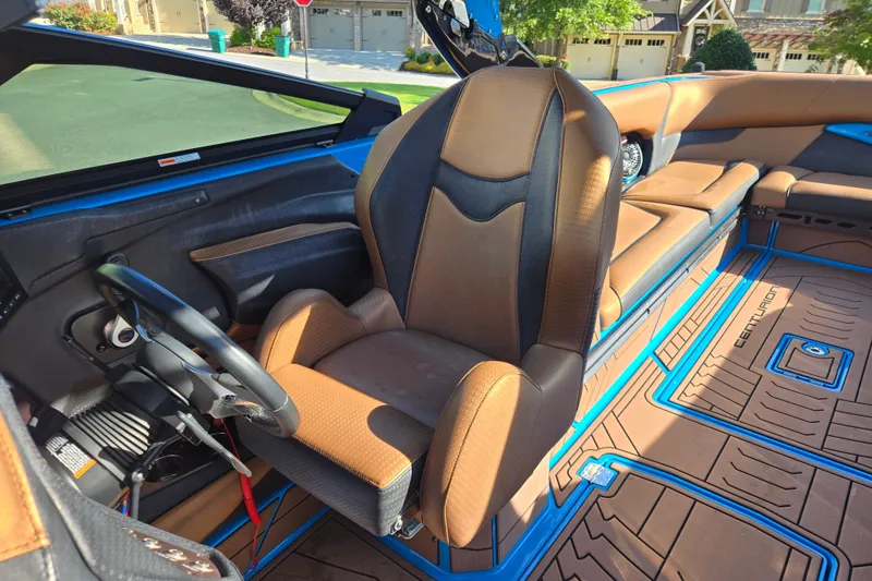 Slide: The Image of 2021 Centurion Ri257 boat interior with brown and black seating, blue accents, and steering wheel. - 17