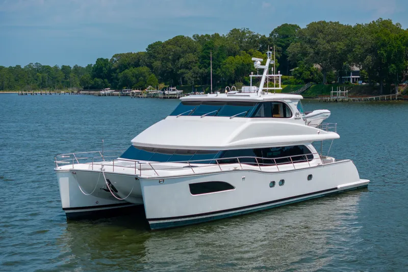 Slide: The Image of Luxurious 2019 Horizon PC65 yacht cruising on a serene lake with lush green surroundings. - 2