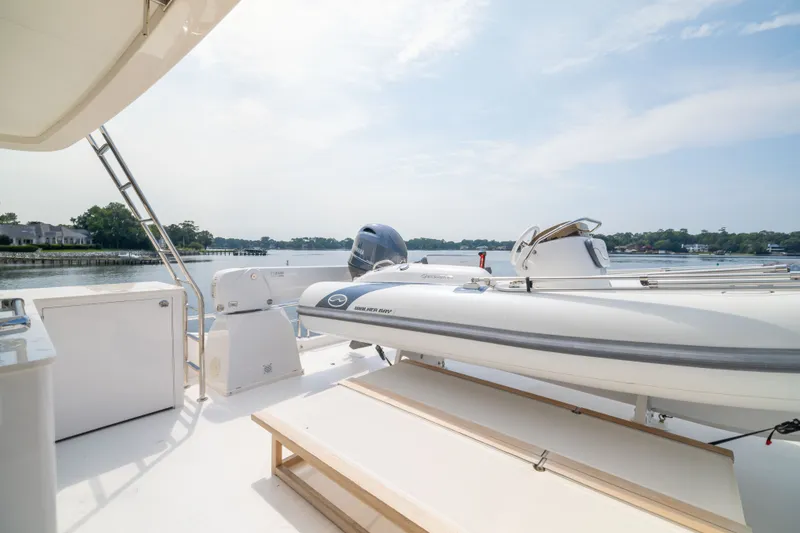 Slide: The Image of Luxury Horizon PC65 yacht deck with tender boat, 2019 model, on serene waterfront. - 10