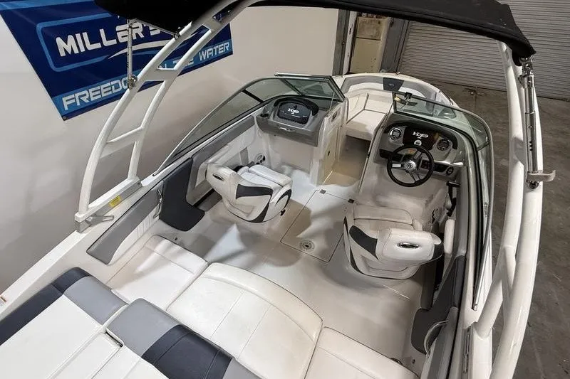 Slide: The Image of 2019 Chaparral 23 H2O Sport boat interior with white seating and steering console. - 13