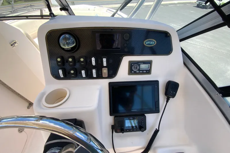 Slide: The Image of Grady-White Freedom 255 boat dashboard with navigation controls, steering wheel, and communication devices. - 12