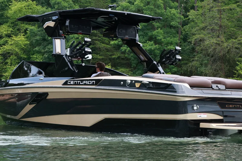 Slide: The Image of 2026 Centurion Ri265 boat cruising on a lake surrounded by lush greenery. - 1