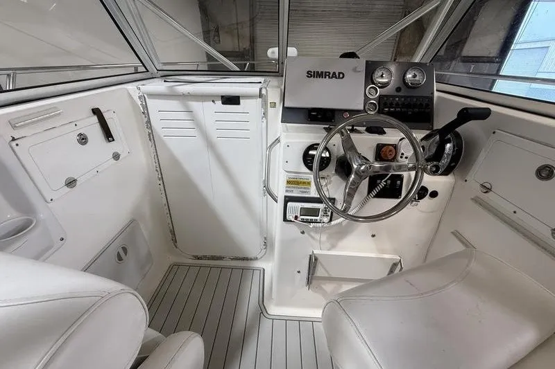 Slide: The Image of 2002 Sea Pro 235 Walk Around boat cockpit with steering wheel and Simrad navigation system. - 16