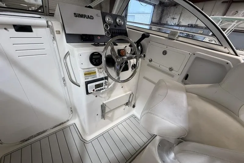 Slide: The Image of 2002 Sea Pro 235 Walk Around boat cockpit with steering wheel and Simrad navigation system. - 17
