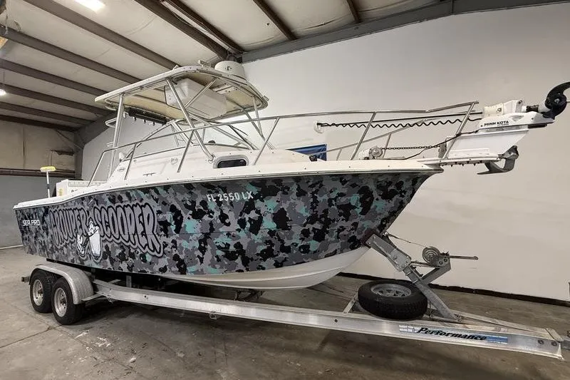 Slide: The Image of 2002 Sea Pro 235 Walk Around boat with camouflage design on trailer in warehouse. - 1