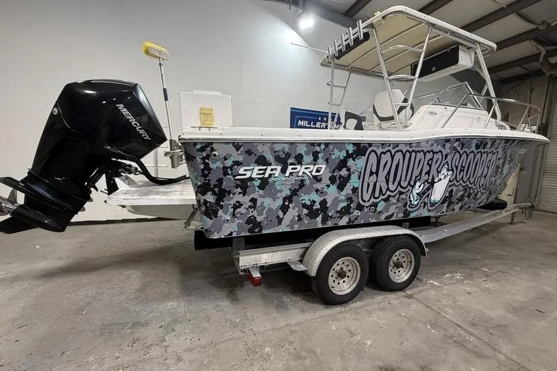 Slide: The Image of 2002 Sea Pro 235 Walk Around boat with camouflage design on a trailer in a garage. - 3