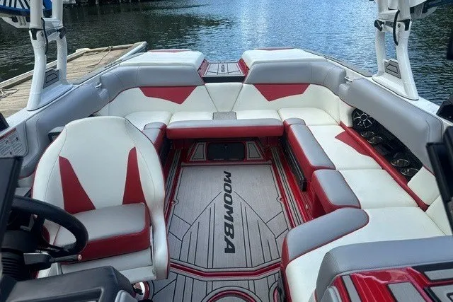 Slide: The Image of 2021 Moomba Kaiyen boat interior with red and white seating, docked by the water. - 17