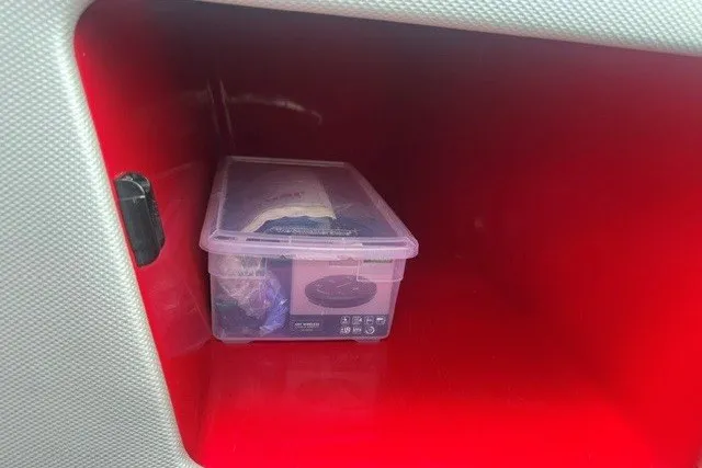 Slide: The Image of Red storage compartment in a 2021 Moomba Kaiyen, containing a plastic container. - 19