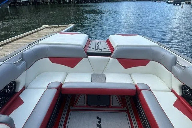 Slide: The Image of 2021 Moomba Kaiyen boat interior with red and white seating, docked by a lake. - 21