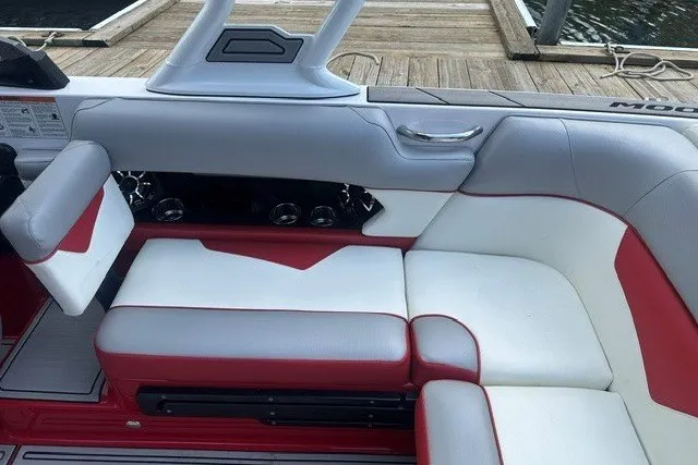 Slide: The Image of 2021 Moomba Kaiyen boat interior with red and white seating, docked by the water. - 14