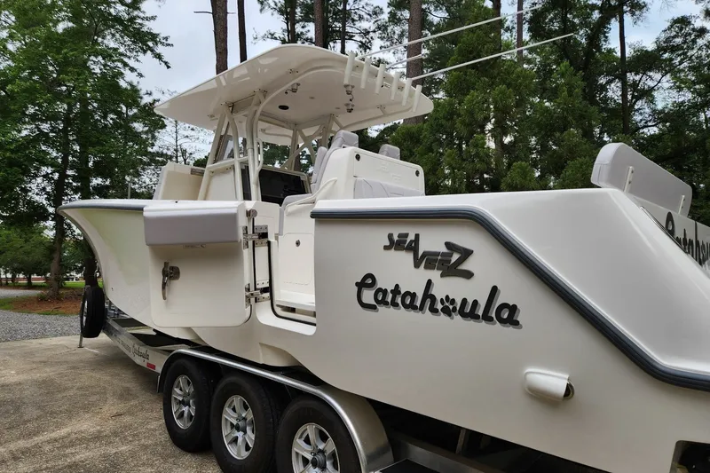 Slide: The Image of 2024 SeaVee 322Z boat on trailer, surrounded by trees, showcasing sleek design. - 1