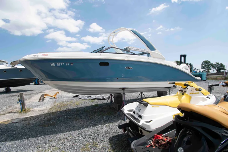 Slide: The Image of 2024 Sea Ray SDX 270 Outboard boat on display beside jet skis, under a clear sky. - 1
