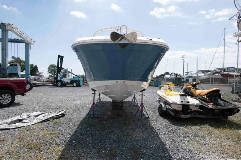 Slide: The Image of 2024 Sea Ray SDX 270 Outboard boat on stands, with jet skis nearby in a marina. - 2