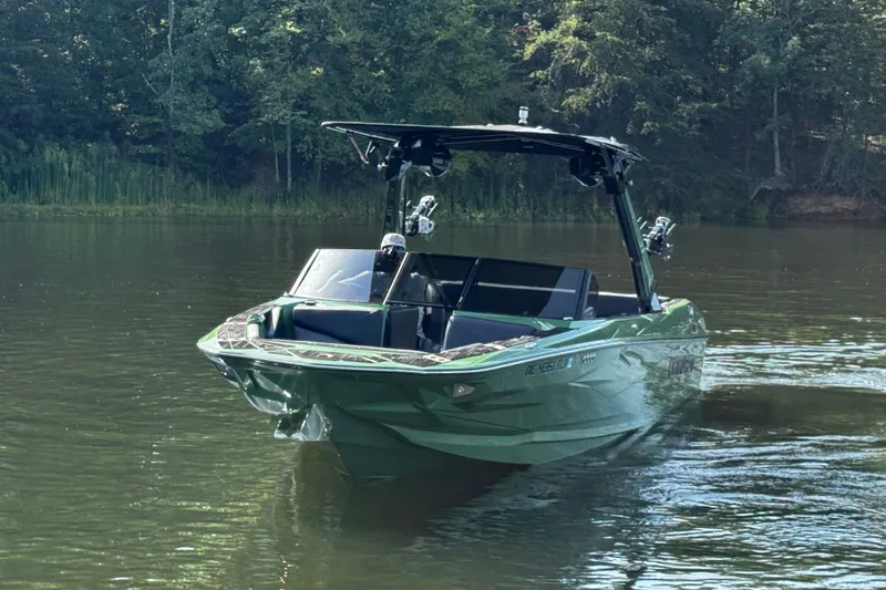 Slide: The Image of 2026 Centurion Nv243 boat cruising on a serene lake surrounded by lush greenery. - 15